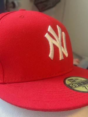 Röd New Era 59FIFTY Yankees keps - Snygg röd New Era 59FIFTY keps med klassiskt New York Yankees broderat vitt logotyp framtill. Flat skärm och klassisk passform. Perfekt för dig som vill ha en stilren och sportig look. Tillverkad i slitstarkt material.