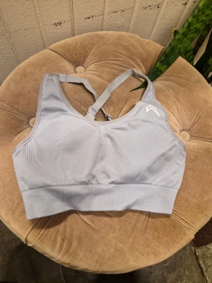 Oner Active sportbh - Säljer en Oner Active sportbh då den tyvärr sitter för tajt på mig. Den sitter riktigt snyggt på ryggen tack vare de dekorativt placerade axelbanden. Skulle säga att den är lite liten i storleken/ compression. Har endast använt den ett fåtal ggr men i tvätten så blev den tyvärr också lite smått lilaaktig i färgen. Det syns mest på "kantbandet".  Jag tycker inte det stör mycket, men den lär inte matcha i färg lika bra om du redan har leggings i samma.