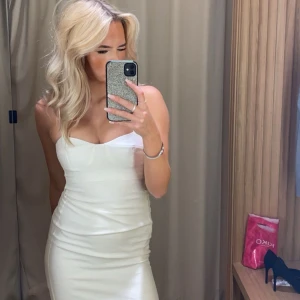 Vit figurnära klänning med tunna band - Säljer en vit, figurnära klänning med tunna axelband och markerad byst. Klänningen har en enkel och elegant design med lätt struktur i tyget. Perfekt för dig som gillar en stilren look. Köpt på mango för ca 800kr