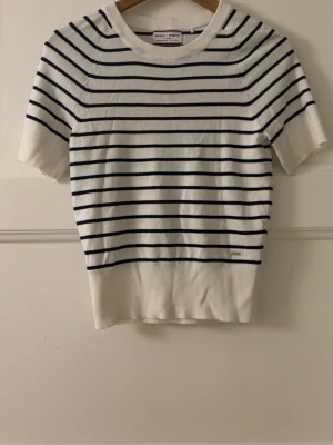 Randig topp från Holly & Whyte - Vit topp med marinblå ränder. Modellen har rund halsringning och korta ärmar. Materialet känns mjukt och stretchigt, perfekt för en stilren look. Klassisk och tidlös design som passar till mycket. Bara att fråga om du undrar något eller vill ha fler bilder! Pris kan diskuteras💞