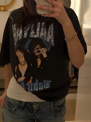 Svart Aaliyah t-shirt med tryck - Cool svart t-shirt med stort Aaliyah-tryck och texten 'Baby Girl' framtill. Oversized passform och korta ärmar, perfekt för en avslappnad streetstyle-look. 