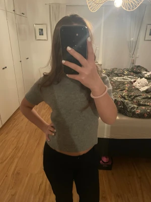 Grå kortärmad stickad tröja - Mysig grå stickad tröja med korta ärmar och rund hals. Tröjan har en enkel, rak passform och är perfekt för lager på lager. Passar till både jeans och kjol.