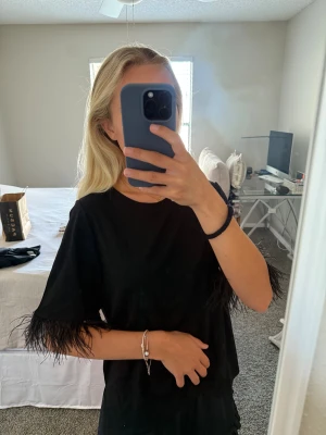 Svart t-shirt - Säljer denna svarta t-shirten med fina detaljer på ärmarna. Köpt på Marshall’s i USA så vet ej exakt märke. Storlek M men passar som en oversized XS. Helt i nyskick!!