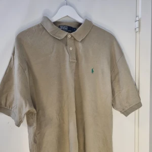 Ralph Lauren pike - Säljer en klassisk pikétröja från Ralph Lauren med korta ärmar. Perfekt för en stilren och avslappnad look.            