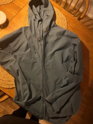 Blå trailjacket från Haglöfs - Välskött snygg trailjacka att ha ovanpå fleecetröja eller sweatshirt.  Bra fritidsplagg som även kan användas som ytterskal vid skidåkning på vårvintern, då det är sol o plusgrader .