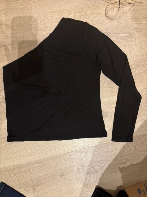 NY: Svart oneshoulder, ribbad tröja, Lindex - Tvättråd: 40°