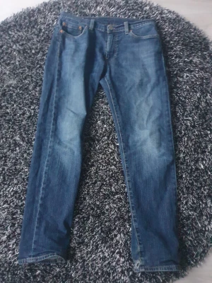 Levi's Premium blå jeans straight fit - Snygga blå jeans från Levi's Premium med klassisk femficksdesign och raka ben. Jeansen har en mörk tvätt med lätt slitning och är tillverkade i slitstarkt bomullsjeansmaterial. Perfekta för dig som gillar en enkel look. Storlek - W30 L32. Använda några få gånger, skriv om du har några frågor!