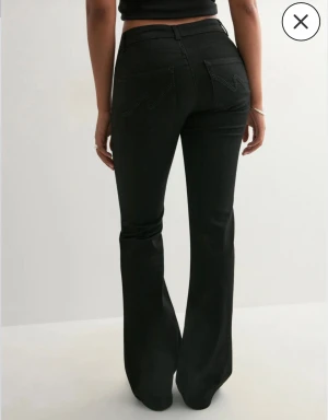 Svarta Bootcut Low waist Nelly jeans - Jätte fina svarta lowwaist jeans från nelly i storlek Small med design på bakfickorna, helt nytt skick, aldrig använt, bara testats, lapp kvar, köptes för 699kr, säljer då jag råka beställa de i fel storlek, skriv vid fler frågor eller bilder, midjemått tvärs över e ungefär 32cm ❤️