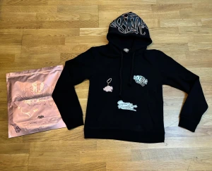 Syna world hoodie gold - Säljer min oanvända syna world hoodie, i storlek M, Ingår originalpåse, stickers och hänglås nyckel ring. Pris kan diskuteras