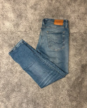 Blå jeans från Jack & Jones - Snygga blå jeans från Jack & Jones med klassisk femficksdesign och läderpatch bak. Jeansen har en slim passform med stretchigt material.   Längd: 30, midja: 32. Pris går att diskutera. Hör gärna av dig vid frågor.