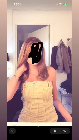 Beige tubtopp med knappdetalj - Säljer en beige jeans tubtopp med snygga sömmar och en knappdetalj framtill. Toppen har en tight passform och är axelbandslös, vilket ger en cool och modern look. Perfekt för dig som gillar att sticka ut med en unik topp i garderoben.