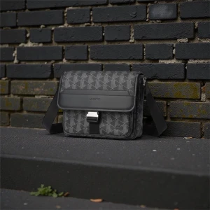 Svart axelväska från Lacoste med mönster - Kvitto och originalförpackning medkommer. Snygg svart axelväska från Lacoste med geometriskt mönster i grått. Väskan har justerbar axelrem, lock med spänne och metallspänne framtill. Tillverkad i syntetmaterial med stilren design och diskret Lacoste-logga på locket.