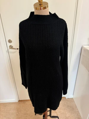 Svart stickad lång tröja Missguided - Svart stickad tröja från Missguided Tall med lång passform och ribbad struktur. Tröjan har hög krage och långa ärmar, perfekt för dig som gillar en enkel och clean look. Snygg att styla med boots eller sneakers.