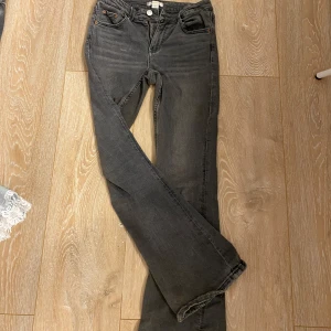 Mörkgrå bootcut jeans - Snygga mörkgrå jeans med bootcut passform och klassisk femficksdesign. Jeansen har en knappstängning och dragkedja framtill. Perfekta för dig som gillar en lite vidare siluett nedtill.