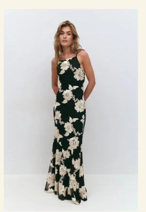 Långklänning  - Supersnygg svart långklänning från Gina tricot med stora champagnefärgade blommor och smala axelband. Använt ett tillfälle, så i princip som ny. Den köptes för 699, säljer för 400