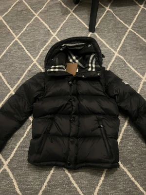 Svart pufferjacka från Burberry (avtagbara armar) - Svart pufferjacka från Burberry med avtagbara ärmar så den kan användas som väst. Låt oss vara vänliga med att inte slösa varandras tid, ställ inte 900 frågor om du inte tänker köpa jackan peace & love 
