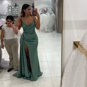 Bal/ fest klänning - Säljer en mintgrön långklänning i satinliknande material med draperad överdel och glittriga detaljer vid bysten. Klänningen är köpt på Diamant mode i Norrköping och har använts endast en gång ( är handtvättad efter användning). Klänningens höga öppning vid benet syddes även ned lite grann av en skräddare. Inga skador. Original pris 4800 —> mitt pris 2400 ☺️