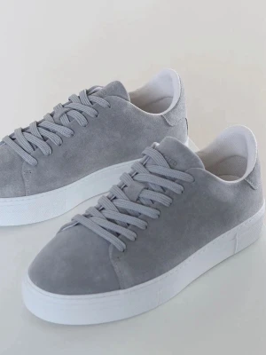 Grå mockasneakers från Selected Homme - Stilrena sneakers i ljusgrå mocka från Selected Homme. Skorna har klassisk rund tå, vita platta sulor och matchande grå snörning. Insidan är fodrad i vitt tyg för extra komfort. Perfekta för en clean och modern look.