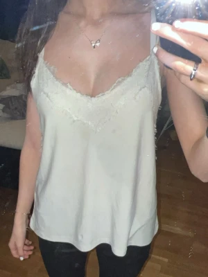 Vit linnetopp med spetsdetaljer - Snyggt vitt urringat linne med väldigt finna spets detaljer. Använd några gånger, men inget man lägger märket till. Och även sitter lite lösare i midjan.