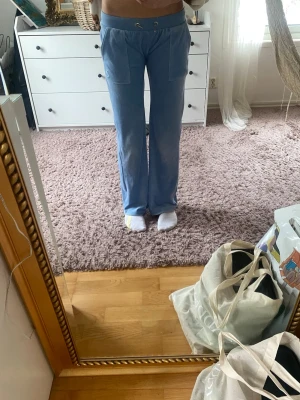 Juicy couture ljusblåa/niebieskie džinsy. - Supermysiga ljusblå mjukisbyxor från Juicy Couture med vida ben och stora fickor framtill. Byxorna har snörning i midjan och är perfekta för en chill och avslappnad stil. Materialet är mjukt och skönt, troligtvis bomull eller polyester.