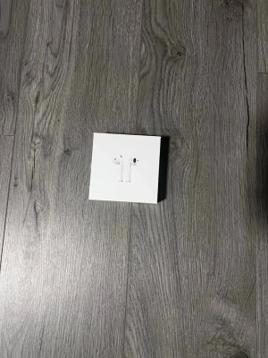 Apple AirPods trådlösa hörlurar - Säljer ett par vita Apple AirPods med laddningsetui. De är trådlösa in-ear hörlurar i klassisk Apple-design, smidiga att använda till både musik och samtal. Kommer i originalförpackning och är tillverkade i plast.