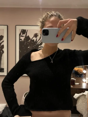 Svart stickad tröja med asymmetrisk urringning - Trendig svart stickad tröja med lång ärm och snygg asymmetrisk urringning. 