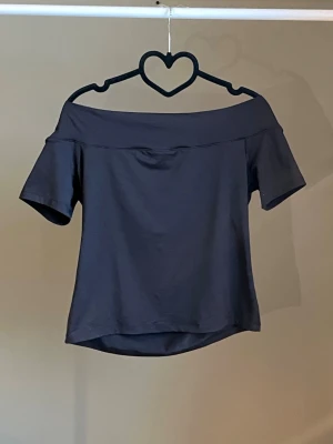 Svart offshoulder topp - Snygg svart offshoulder topp med korta ärmar och bred kant upptill. Enkel och stilren design som passar perfekt till jeans eller kjol. Tillverkad i mjukt material för en bekväm känsla. Köpt från H&M inprincip aldrig använd!🖤