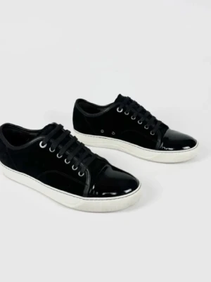 Svarta Lanvins sneakers med lackdetaljer - Stilrena Lanvins svarta sneakers med blankt lack på tån och klassisk vit sula. Skorna har snörning och en mix av mocka och syntetmaterial som ger en schysst kontrast. Perfekta för dig som gillar en clean och modern look.