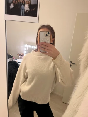 Vit oversized stickad tröja - Säljer en vit, oversized stickad tröja med rund hals och långa ärmar. Tröjan har ribbade muddar vid ärmslut och nederkant, vilket ger en snygg och avslappnad look. Perfekt att matcha med jeans eller kjol för en trendig stil.