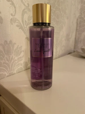 Victoria's Secret mist - Fräsch body mist från Victoria's Secret i doften Love Spell. Flaskan är genomskinlig med lila vätska och har ett snyggt guldigt lock. Rymmer 250 ml och har en modern, stilren design som passar perfekt på sminkbordet.