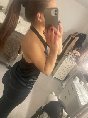 Svart omlott halterneck-top från Bik Bok - Säljer en svart halterneck-top från Bik Bok i storlek S. Materialet är glansigt och känns mjukt mot huden