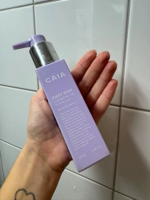 CAIA First Step Cleansing Oil  - Lila pumpflaska med CAIA First Step Cleansing Oil, 100 ml. Oljan innehåller solrosolja, sötmandelolja och vitamin E. Passar alla hudtyper och är dermatologiskt testad samt vegansk. Snygg och stilren design, perfekt för sminkborttagning. Ungefär halva innehållet kvar alltså 50ml. Helt slutsåld online! 