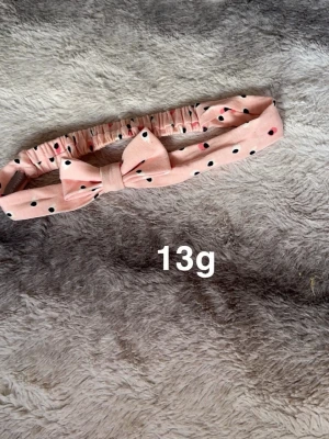 Rosa prickigt hårband med rosett - Säljer ett gulligt rosa hårband med svarta och vita prickar samt en stor rosett framtill. Perfekt accessoar för att piffa upp din look. Hårbandet är elastiskt och sitter bekvämt på huvudet.🌸 Fint använt skick