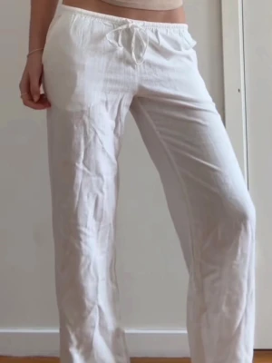 Vita linnebyxor med snörning - Populära vita linnebyxor från H&M med vida/raka ben och midja med snörning. Perfekta för varma dagar, de är lätta och luftiga. Materialet är linne och färgen är helt vit. 