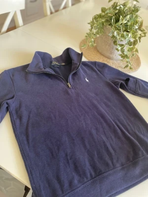 Marinblå half zip tröja Polo Ralph Lauren - Säljer en marinblå långärmad tröja från Polo Ralph Lauren med half zip och broderad logga på bröstet. Tröjan har en klassisk ståkrage och är i bomull. Perfekt för dig som gillar stilren och enkel design. Storlek M men passar mer som S. Hör av dig vid frågor!