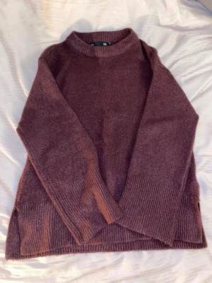 Vinröd stickad tröja från 157 - Mysig vinröd stickad tröja från 157 i storlek XS. Tröjan har en rund halsringning, långa ärmar och breda ribbade muddar vid ärmslut och nederkant. Perfekt för kyliga dagar och enkel att matcha med jeans eller kjol.