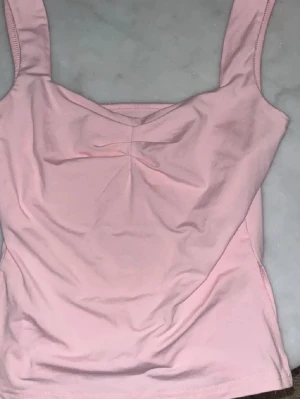 Ljusrosa linnetopp  - Säljer en söt ljusrosa linnetopp med twistad detalj vid bröstet och slit vid sidorna ej använd