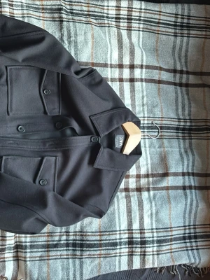 Svart overshirt från Zara - Svart overshirt från Zara med klassisk krage och stora bröstfickor med knappar. Jackan har en rak och loose passform, knäppning framtill och är långärmad. Perfekt att slänga över en hoodie eller t-shirt för en chill look.