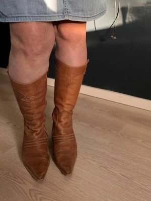 Bruna cowboy boots med spetsig tå - Säljer ett par snygga bruna cowboy boots i äkta skinn, mammas 20 årings gamla.  
