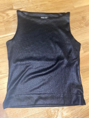 Svart skimmrig linnetopp från BSB club - Snygg svart linnetopp från BSB club med skimmrigt tyg som ger en cool shimmer-effekt. Ingen strl står gissar på S eller Xs