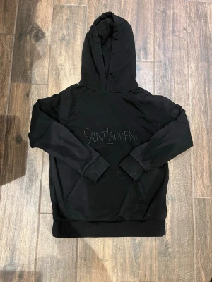 Saint lauren hoodie - Säljer en super snygg hoodie från yves saint lauren! Är i super bra skick och är äkta. Passar om man är mellan 174-183. Pris är diskuterbart! Skriv för mer bilder🤩