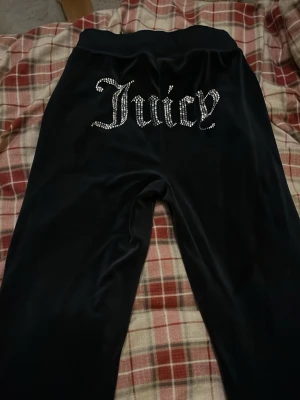 Marin blåa Juicy Couture mjukisbyxor XS - Marin blåa mjukisbyxor från Juicy Couture i storlek XS. Byxorna har glittrande strassdetaljer med texten 'Juicy' på baksidan och en liten JC-logga på framsidan. Mjukt och lent material med bred midja och snörning framtill för extra komfort.