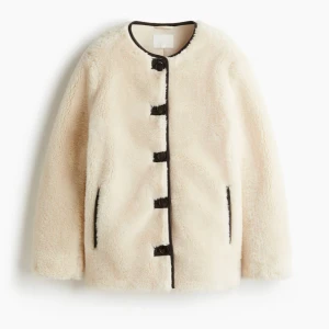 Beige teddyjacka med svarta detaljer - Säljer en  beige teddyjacka med svarta knappar och svarta detaljer vid fickor och kanter. Jackan har rund halsringning och långa ärmar, perfekt för dig som vill ha en mysig och trendig look. Nypris 549, lappen kvar, helt slutsåld💗