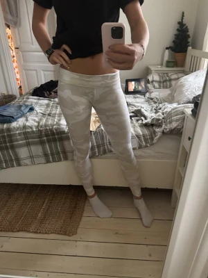 Vita camo leggings Calvin Klein  - Säljer ett par snygga vita leggings från Calvin Klein Performance i storlek S. De har ett diskret camouflage-mönster i ljusa toner och hög midja. Materialet är stretchigt och passar perfekt till träning eller chill. Superskön passform och riktigt fräsch look.