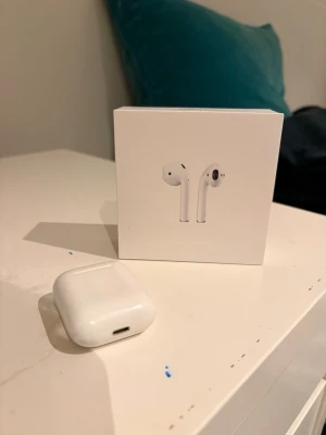 Apple AirPods med laddningsetui (A2032, A2031, A1602) - Säljer ett par Apple AirPods med laddningsetui, modell A2032/A2031/A1602. Fungerar med iOS, Mac och Apple Watch. Skick: synligt smuts och slitage på etuiet och hörlurarna, men fullt fungerande. Originalförpackning medföljer.