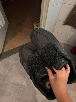 New Balance 9060 Black - Säljer ett par svarta New Balance sneakers med chunky sula och meshpaneler för extra ventilation. Skorna har snörning och en rund tå, med detaljer i både syntet och skinn. Perfekt för dig som gillar sportig och modern stil. Endast använda enstaka gång inte min stil. Kan skicka fler bilder om önskas. Nypris 2250kr idag på deras hemsida. 