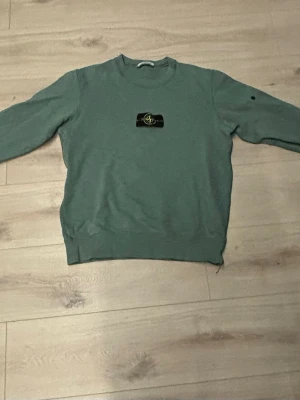Grön Stone Island jumper - Säljer en grön Stone Island jumper med ett lite hål på tröjarmen