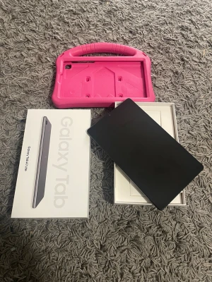 Samsung Galaxy Tab A7 Lite | 32 GB - Samsung Galaxy Tab A7 Lite 32 GB med rosa skyddsfodral och instruktionsbok.  Original låda ingår samt laddningskabel.  Fungerar fint.  Inga sprickor utan hel, någon mindre repa finns som på vilken begagnad produkt som helst.   På bild 3 kan man se att höljet höjt sig lite från ett mindre tapp m.  Modell: SM-T220  Med Samsung Galaxy Tab A7 Lite WiFi surfplatta kan du ta med dig all underhållning när du är på resande fot. Dolby Atmos-högtalarna tillsammans med skärmen på 8.7 tum ger en otrolig fil