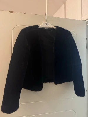 Svart pälsjacka från Gina Tricot - Säljer en svart pälsjacka från Gina Tricot i storlek S. Jackan har en mjuk och fluffig yta, rak passform och långa ärmar. Perfekt för dig som vill ha en stilren och mysig look med lite extra attityd.