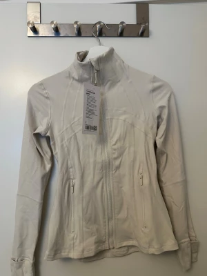Lululemon define jacket  - Helt ny, supersnygg define jacket från Lululemon. Säljer den pga den är för liten för mig så har inte kunnat använda den. US size 2 vilket motsvarar XS.  Färgen heter Light Ivory. 